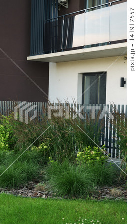 Modern apartment building balancing city living with green landscaping and ornamental grasses Modern apartment building balancing city living with green landscaping and ornamental grasses 141917557