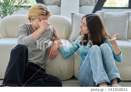 Young woman comforts upset boyfriend after conflict, sitting on living room floor Young woman comforts upset boyfriend after conflict, sitting on living room floor 141918031