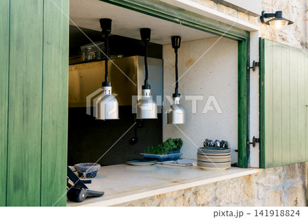 Open restaurant serving window with kitchen counter and heat lamps ready for service. Concept of hospitality, cuisine, dining and business 141918824