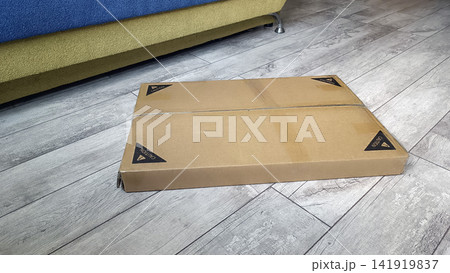 Cardboard box with caution labels on wooden floor near colorful sofa.... 141919837