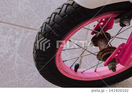 Close up view of rusty metal front wheel hub and pink rim on old neglected kids bicycle concept of bad storage weather damage and need for maintenance photo Close up view of rusty metal front wheel hub and pink rim on old neglected kids bicycle concept of bad storage weather damage and need for maintenance photo 141920102