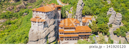 Panoramic aerial drone view of Rousanou Monastery built on steep rock formation surrounded by green forest trees in Meteora region near Kalambaka Thessaly Greece photo 141920120