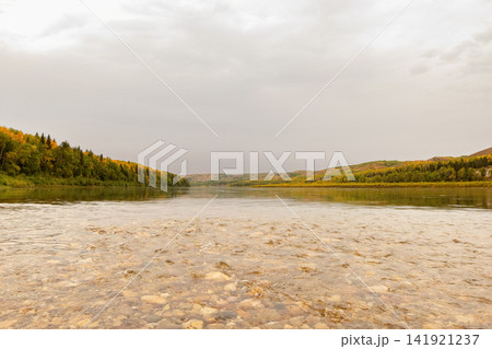 Calm warm autumn day at the river among yellow forests. 141921237