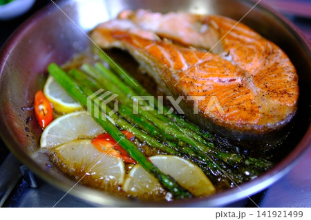 Step by step pan fried salmon steak recipe with fresh trout fillet seasoning oil and golden crust cooking process in black frying pan for homemade seafood meal 141921499
