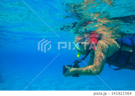 Man with photo camera taking photos and snorkeling underwater by coral reef in the Red sea, Egypt 141921564