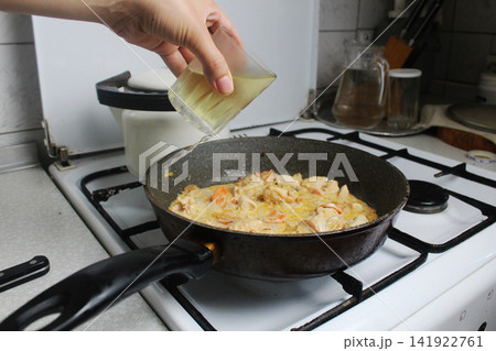 Girl adds white wine to sauce. Girl adds white wine to sauce. 141922761
