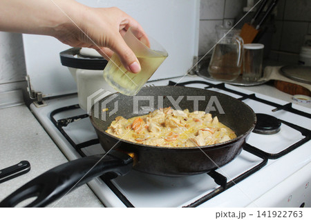 Girl Adding Broth bouillon To Chicken Pan. 141922763