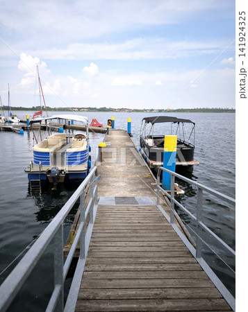 Wooden pier with moored pontoon boats on the lake. Bitterfeld, Goitzsche Wooden pier with moored pontoon boats on the lake. Bitterfeld, Goitzsche 141924325