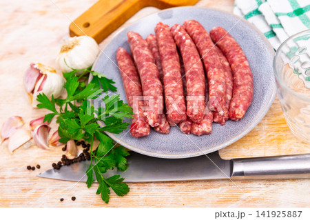 Plate of raw longaniza wit greens, garlic and spices prepared for cooking 141925887