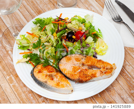 Two fried salmon steaks with vegetable salad 141925889