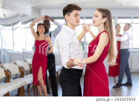 Group of multinational sports people rehearsing social dance in dance hall Group of multinational sports people rehearsing social dance in dance hall 141925933