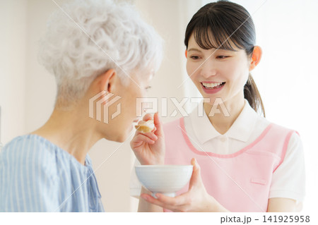 お粥を食べさせてもらう日本人シニア女性と若い日本人看護師 お粥を食べさせてもらう日本人シニア女性と若い日本人看護師 141925958