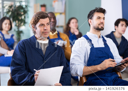 Multinational group workers listens and takes notes lectures in lecture hall Multinational group workers listens and takes notes lectures in lecture hall 141926376