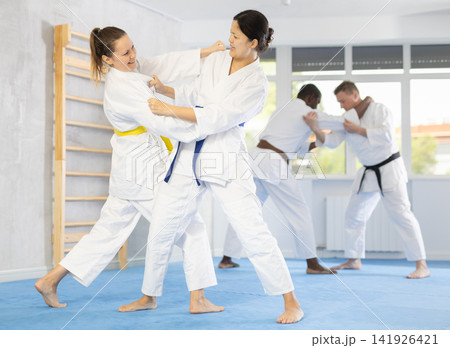 Middle-aged female judo practitioners engaged in wrestling in sports hall Middle-aged female judo practitioners engaged in wrestling in sports hall 141926421