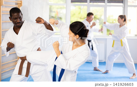 Middle-aged man attendee of karate classes fighting with his opponent in sports hall 141926603