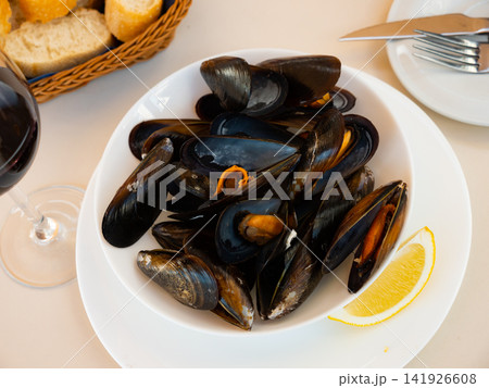 Gourmet seafood tapas. Steam cooked mussels garnished with lemon slice on plate 141926608