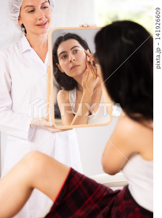 Young woman examining her face after cosmetic procedure 141926609