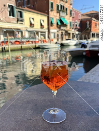 イタリア・ムラーノ島の運河を眺めるテラス席とオレンジ色のカクテル イタリア・ムラーノ島の運河を眺めるテラス席とオレンジ色のカクテル 141927214