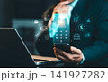 Businessman using smartphone with virtual online banking application hologram interface and financial icons, mobile payment and e-banking concept. 141927282