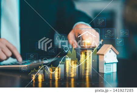 Businessman touching virtual house icon on growing gold coin stacks with rising financial graph and house model, property investment concept. 141927285