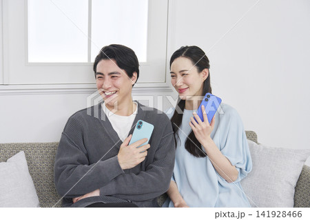 リビングでスマホを持っているカップルのポートレート カメラ目線 リビングでスマホを持っているカップルのポートレート カメラ目線 141928466