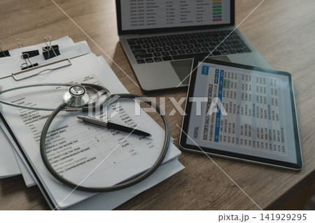 Medical data Stethoscope rests business report beside tablet and laptop screens displaying doctor appointment schedules, healthcare administration and clinical operations planning. Medical data Stethoscope rests business report beside tablet and laptop screens displaying doctor appointment schedules, healthcare administration and clinical operations planning. 141929295