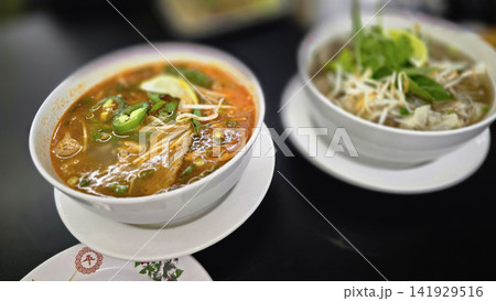 Vietnamese Pho Noodle Soup With Fresh Herbs, Lime And Crispy Spring Rolls On Table Vietnamese Pho Noodle Soup With Fresh Herbs, Lime And Crispy Spring Rolls On Table 141929516