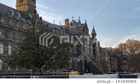 Georgetown University's majestic, gray stone Gothic building with towers. Trees grow in front of the facade, and construction is underway in the foreground. Georgetown University's majestic, gray stone Gothic building with towers. Trees grow in front of the facade, and construction is underway in the foreground. 141930003