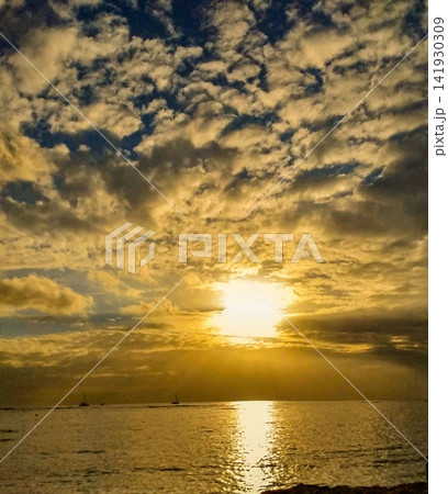 黄金色の雲と海に映る太陽の光、ドラマチックな夕日の風景 黄金色の雲と海に映る太陽の光、ドラマチックな夕日の風景 141930309
