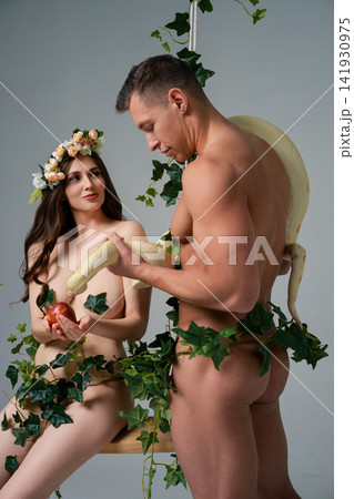 Couple poses together with a snake in a studio setting surrounded by greenery Couple poses together with a snake in a studio setting surrounded by greenery 141930975
