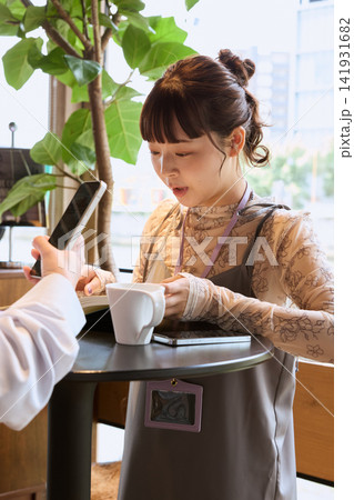 カフェでコーヒーを飲みながら打ち合わせをする女性たち カフェでコーヒーを飲みながら打ち合わせをする女性たち 141931682