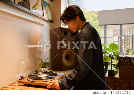 レコードプレーヤーでアナログレコードを再生する若い男性 レコードプレーヤーでアナログレコードを再生する若い男性 141931733