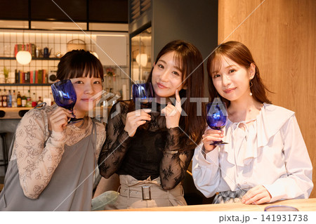 バーでワイングラスを持って楽しむ3人の若い女性 バーでワイングラスを持って楽しむ3人の若い女性 141931738
