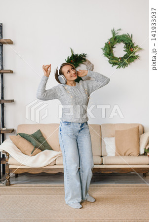Woman listening music headphones dancing living room Christmas Woman listening music headphones dancing living room Christmas 141933037