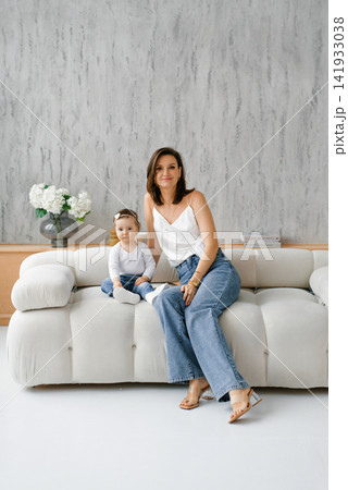 Mother and Baby Daughter Sitting on Sofa Mother and Baby Daughter Sitting on Sofa 141933038
