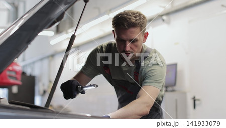 Repairman working on an usual car maintenance. Professional mechanic is working on a car in a car service. 141933079