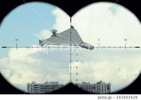 Military drone seen through binocular crosshairs above city skyline 141933429