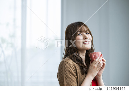 窓際でコーヒーを飲む若い女性 141934163