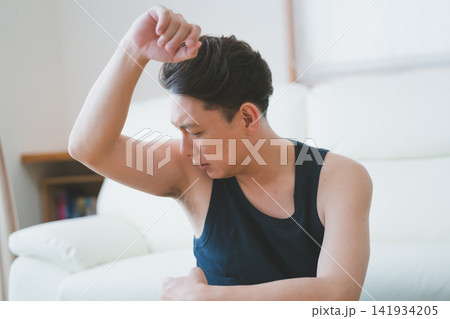 眉間にシワを寄せて脇の臭いを確認する40代男性のメンズボディケア 141934205