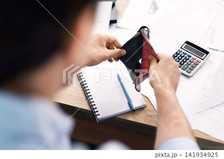 man holds an empty wallet over a desk with bills and a calculator, struggling with financial expenses, high cost of living, inflation, and a money crisis. man holds an empty wallet over a desk with bills and a calculator, struggling with financial expenses, high cost of living, inflation, and a money crisis. 141934925