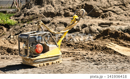A machine is processing soil on a construction site. The area is busy with dirt and construction materials. Workers may be preparing for a new project 141936418