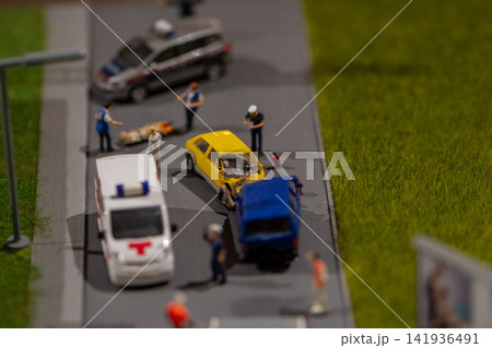 Miniature emergency responders examine crash between yellow car and blue van Miniature emergency responders examine crash between yellow car and blue van 141936491