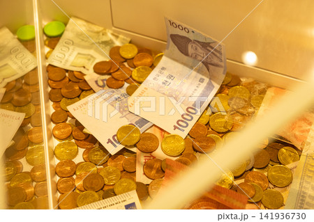 Donation box filled with international banknotes and coins for charity Donation box filled with international banknotes and coins for charity 141936730