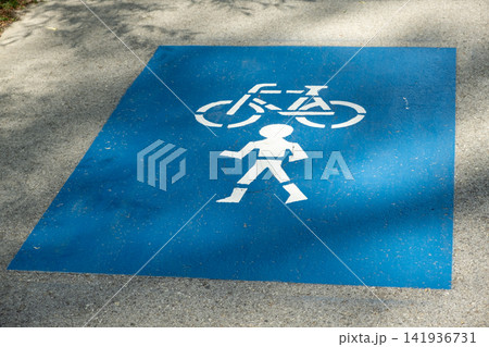 Blue road marking indicating a shared pedestrian and bicycle lane on the asphalt Blue road marking indicating a shared pedestrian and bicycle lane on the asphalt 141936731