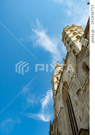 Old stone church architecture rising into blue sky with light clouds Old stone church architecture rising into blue sky with light clouds 141936753