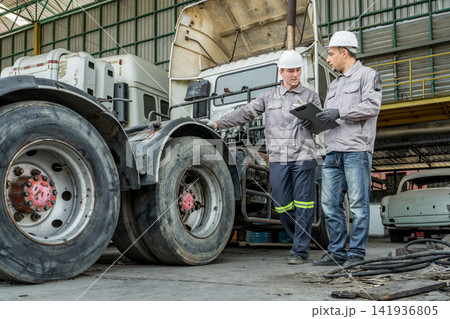 Mechanics inspecting heavy-duty truck wheels in repair shop for maintenance efficiency. 141936805