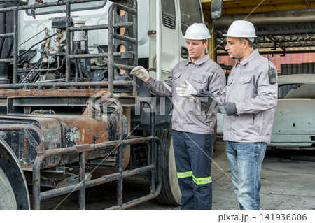 Two mechanics inspecting truck engine components in garage for maintenance 141936806
