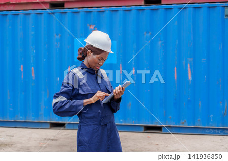 Black woman wearing hard hat reviewing data on tablet at construction site Black woman wearing hard hat reviewing data on tablet at construction site 141936850