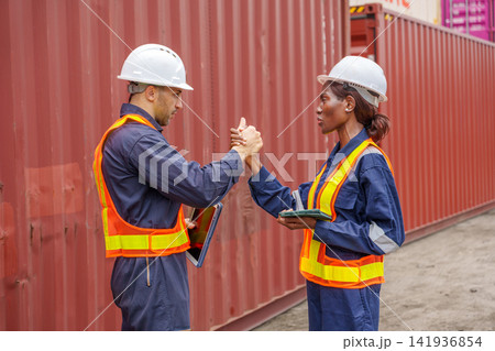 Two construction workers collaborating on project at shipping yard. Two construction workers collaborating on project at shipping yard. 141936854