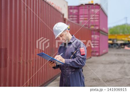 Cargo worker inspecting shipping containers at port for logistics management. Cargo worker inspecting shipping containers at port for logistics management. 141936915